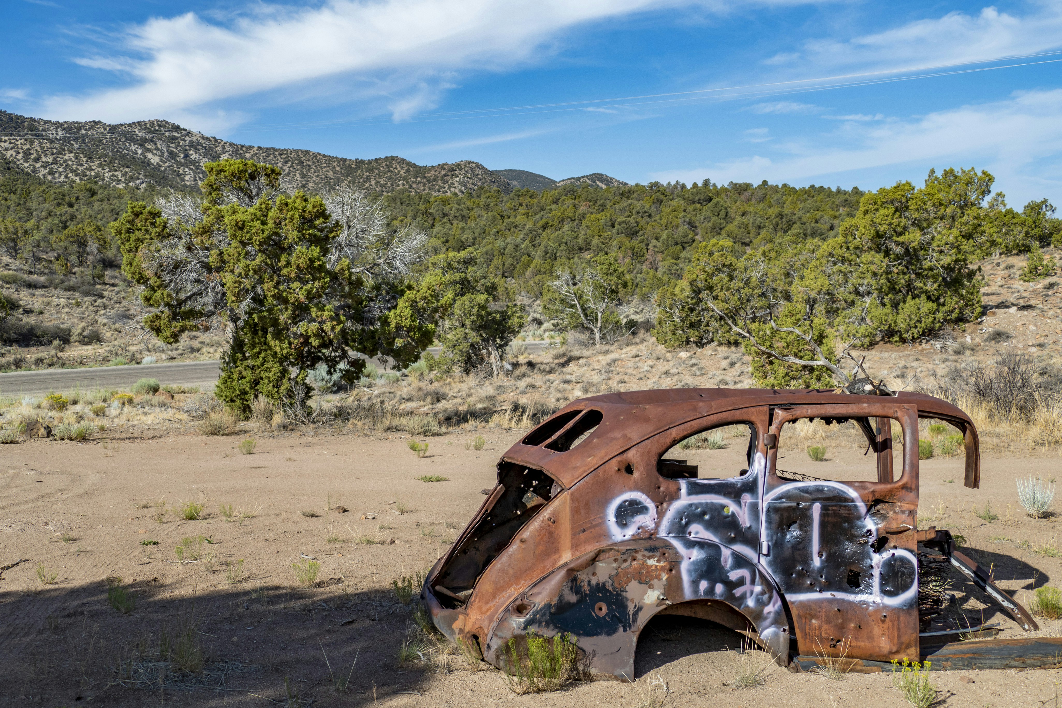 an old rusted out car with graffiti on it