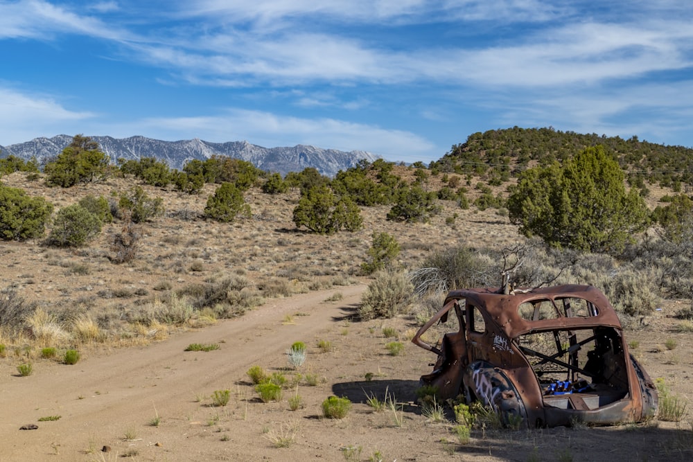 a rusted out car sitting in the middle of a desert