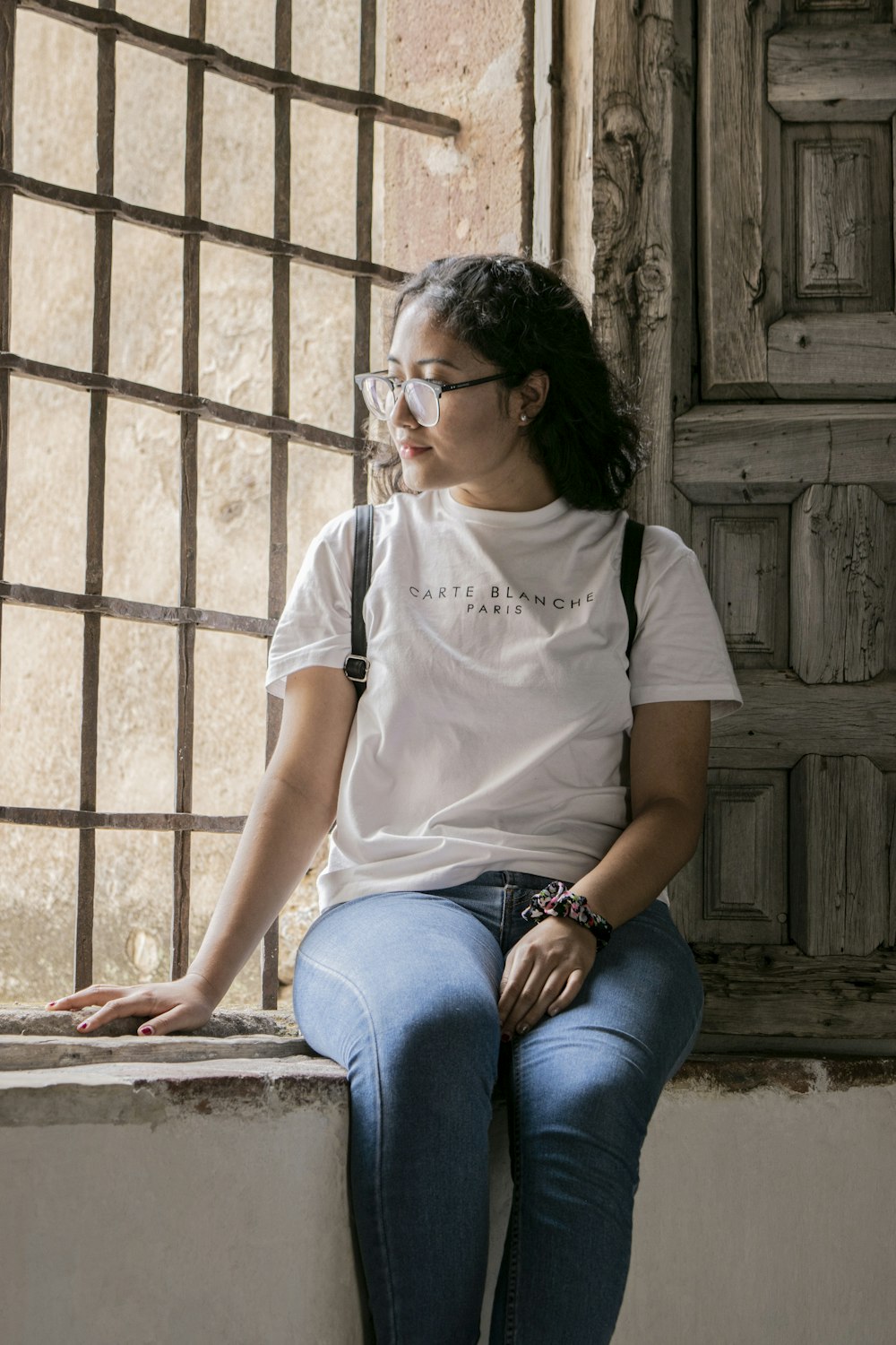 a woman sitting on a ledge looking out a window