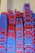 A large stack of plastic chairs arranged neatly against a wall. The chairs are predominantly blue and red, with each stack reaching considerable height, displaying a pattern created by alternating colors. The letters 'NTL' are visible on multiple chairs.