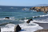 A panoramic view of a rocky coastline with crystal-clear waves crashing below