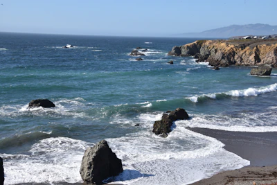 A panoramic view of a rocky coastline with crystal-clear waves crashing below