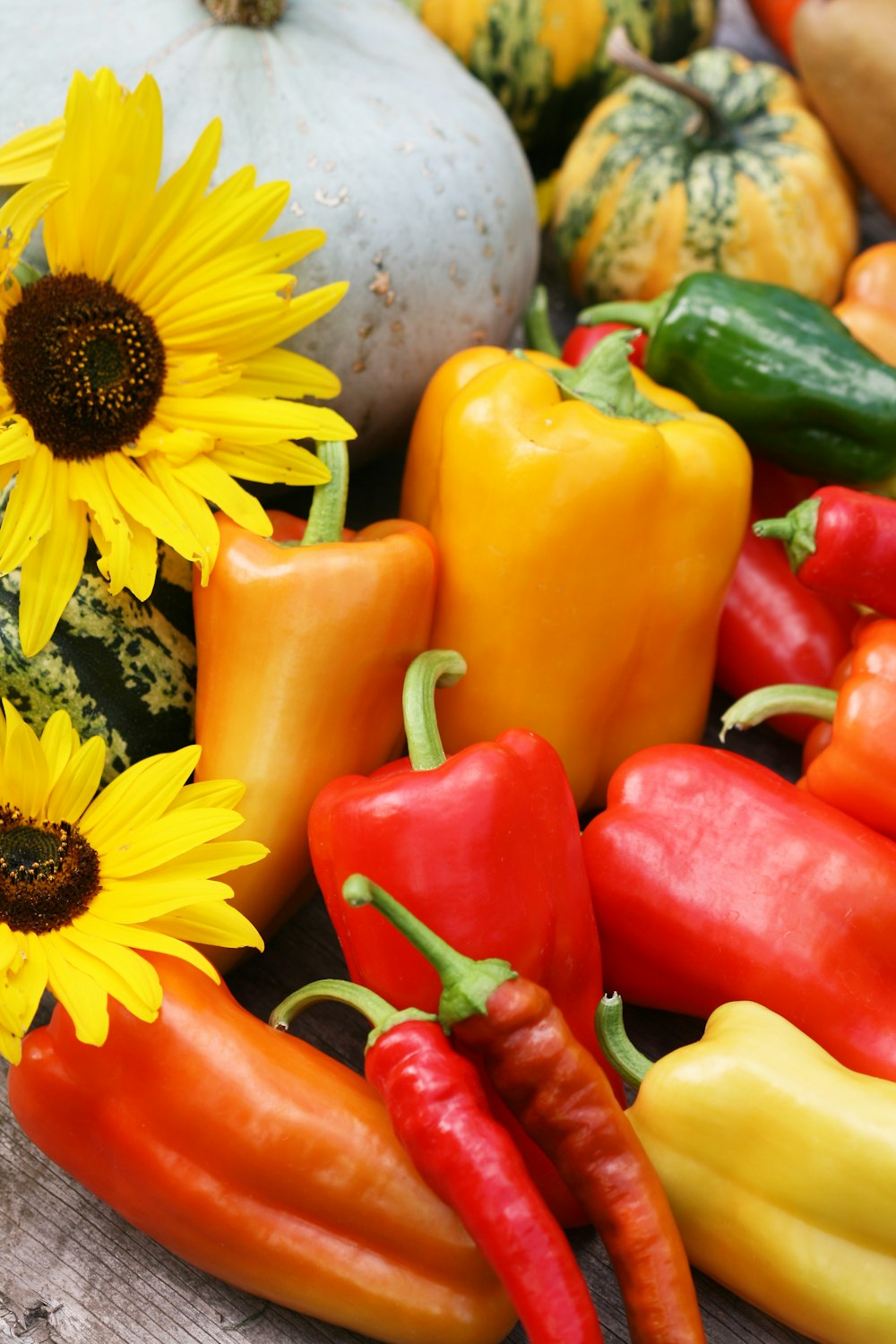 a bunch of peppers and sunflowers on a table