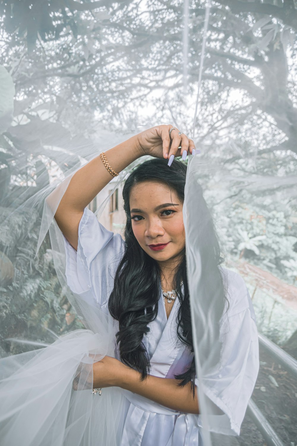 a woman in a white dress is holding a veil over her head