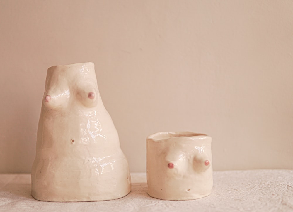 two white ceramic vases sitting on top of a table
