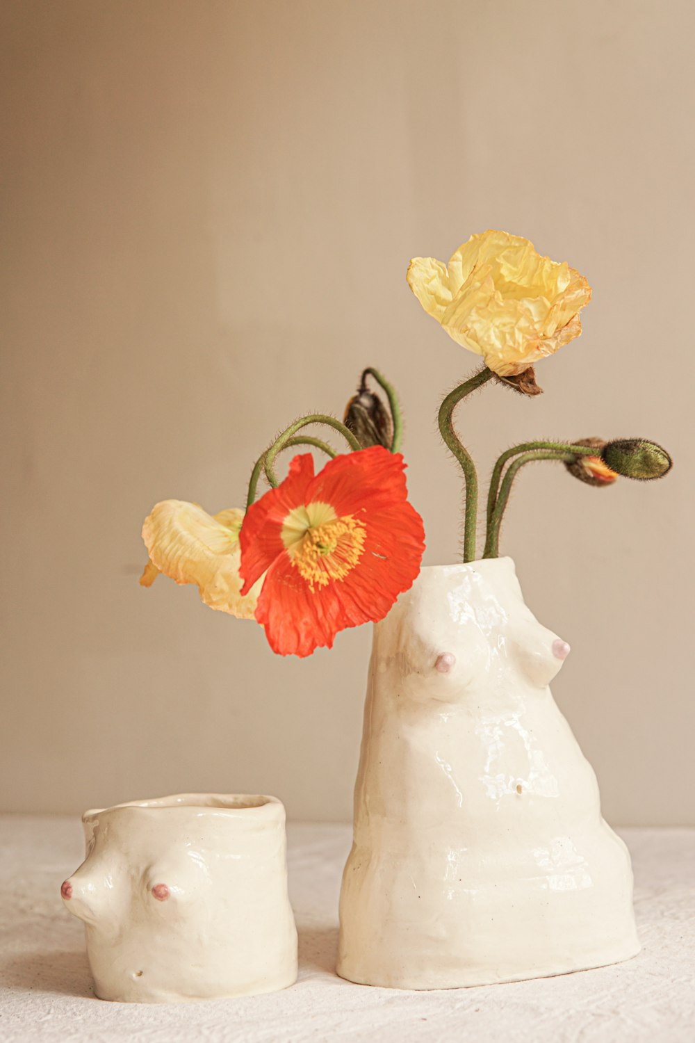 two white vases with flowers in them on a table