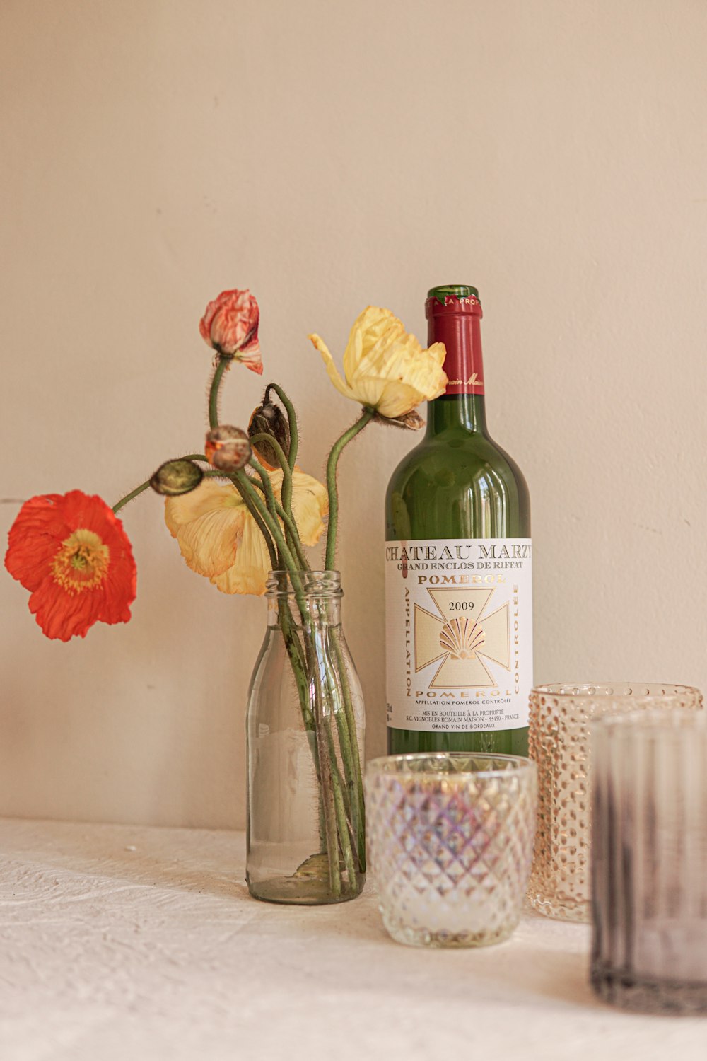 a bottle of wine sitting next to a vase with flowers in it