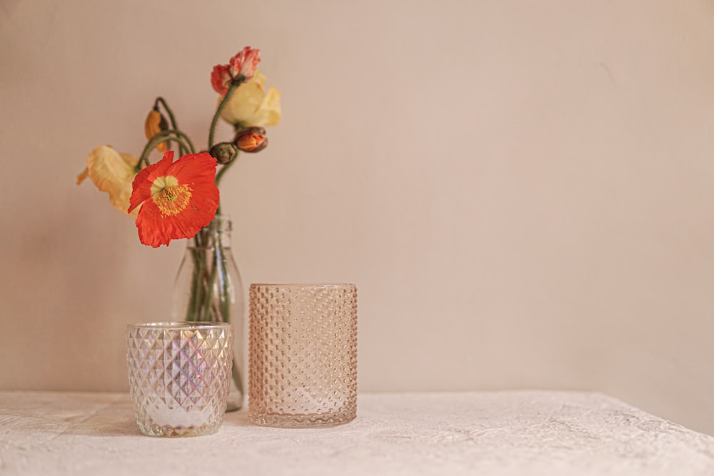 two vases with flowers in them sitting on a table