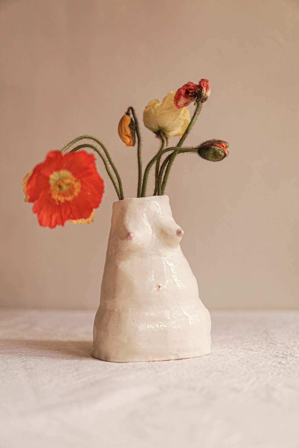 a white vase with flowers in it on a table