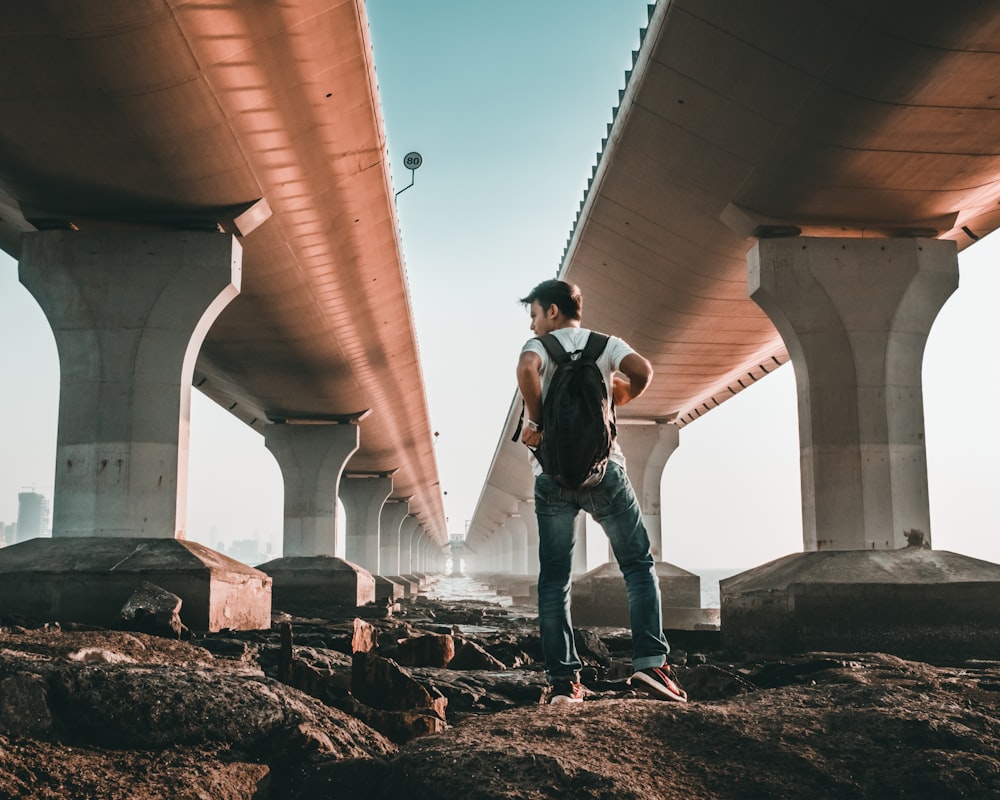 a man standing under a bridge with a backpack