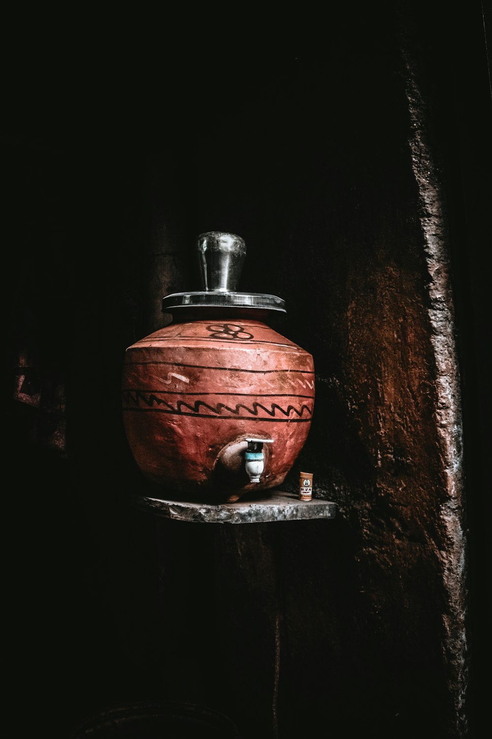 a clay pot sitting on a shelf in a dark room