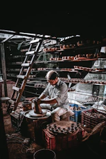 Employees gathered around a pottery wheel, shaping clay with focused smiles in a cozy studio.