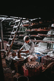Artisan at work shaping clay on a pottery wheel in a warmly lit studio.