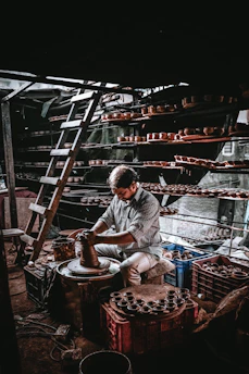 Artisan at work shaping clay on a pottery wheel in a warmly lit studio.