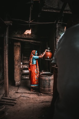 a woman in a colorful sari is pouring water