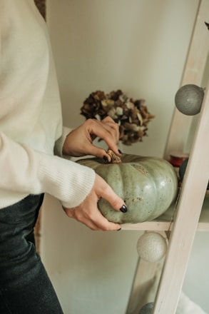 a woman is decorating a green pumpkin