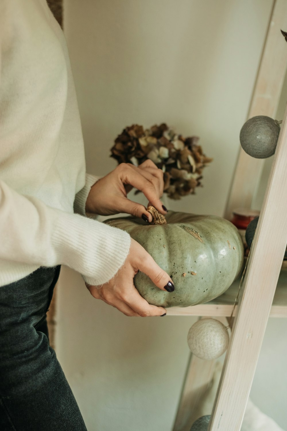 a woman is decorating a green pumpkin