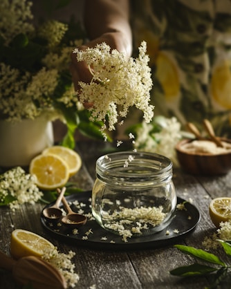 a person sprinkling flowers into a jar of water