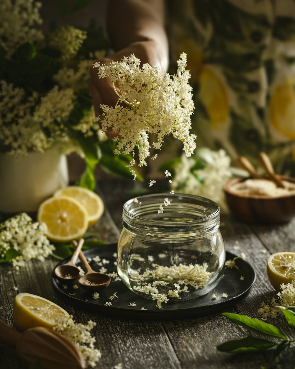 a person sprinkling flowers into a jar of water