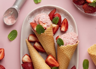 three cones of ice cream with strawberries on a plate