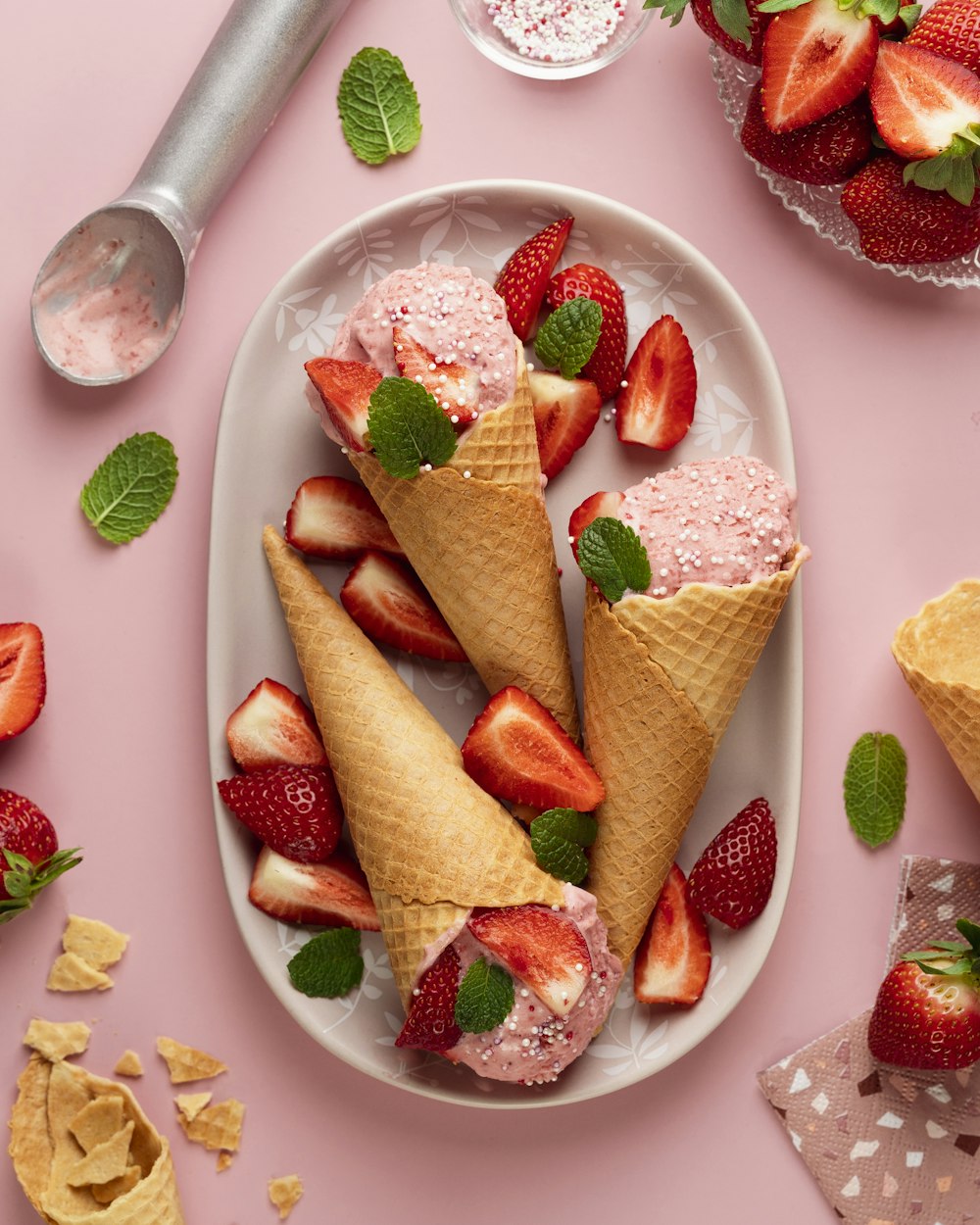 three cones of ice cream with strawberries on a plate
