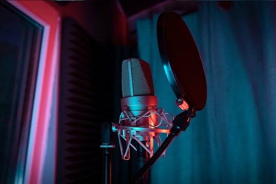 A close-up of a sleek condenser microphone glowing softly in a cozy recording studio.