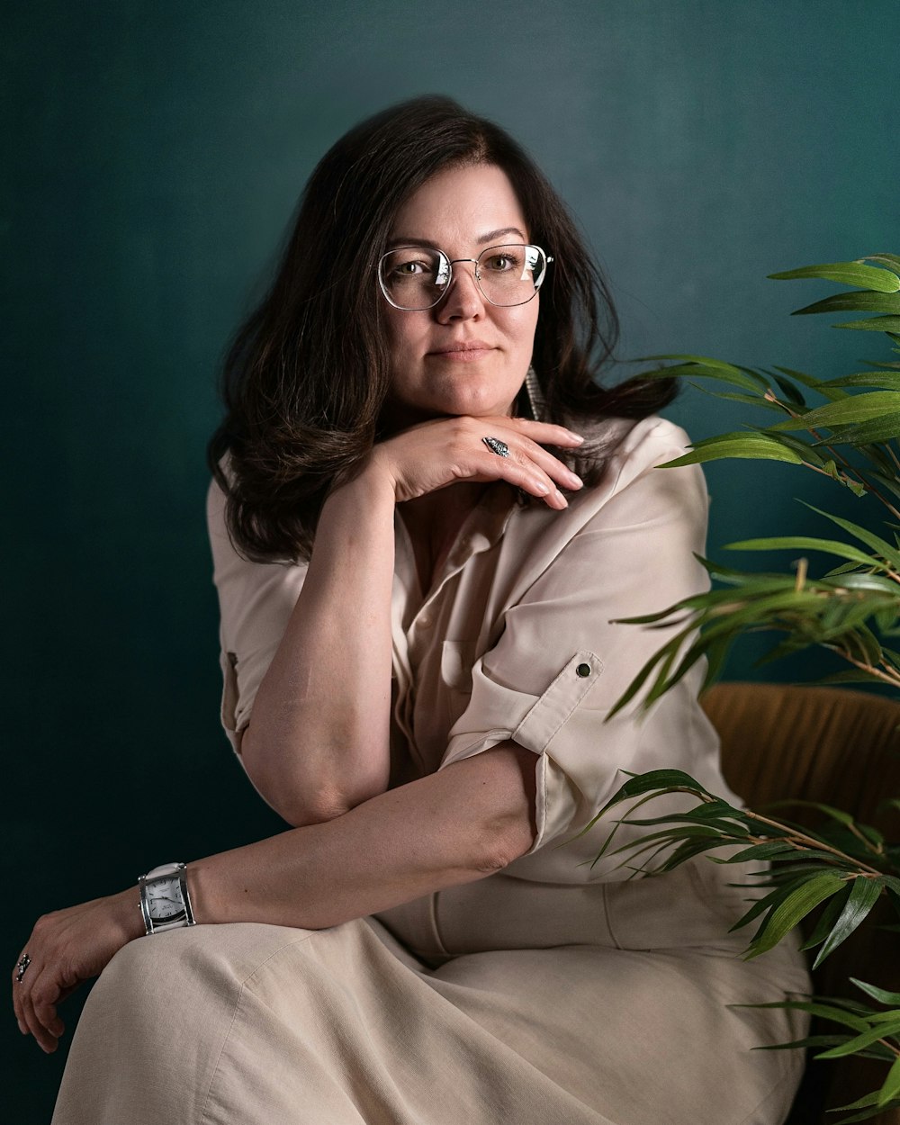 a woman sitting on a chair next to a potted plant