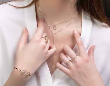 a close up of a person wearing rings and a necklace