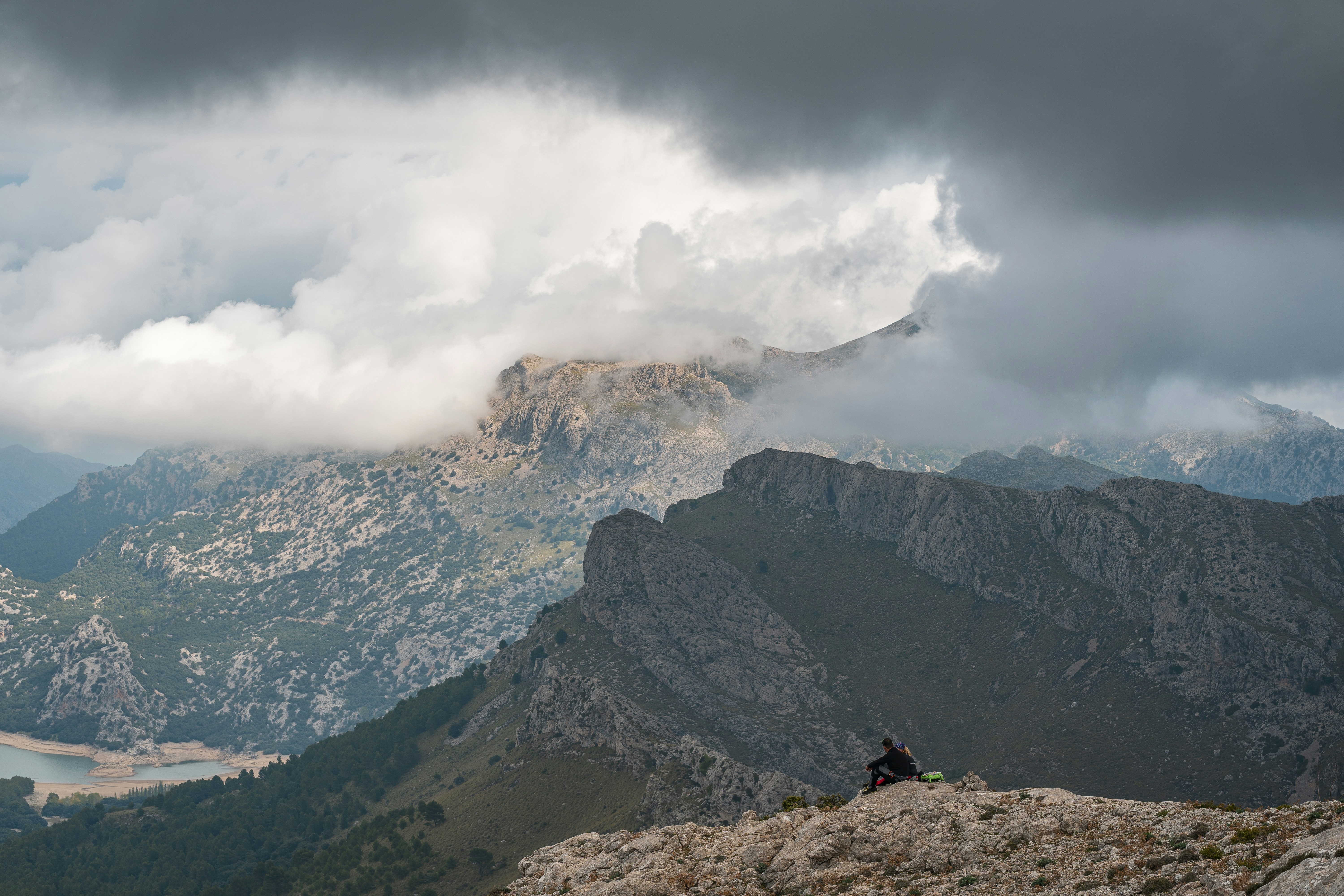 湖のほとりの山の上に座っている男