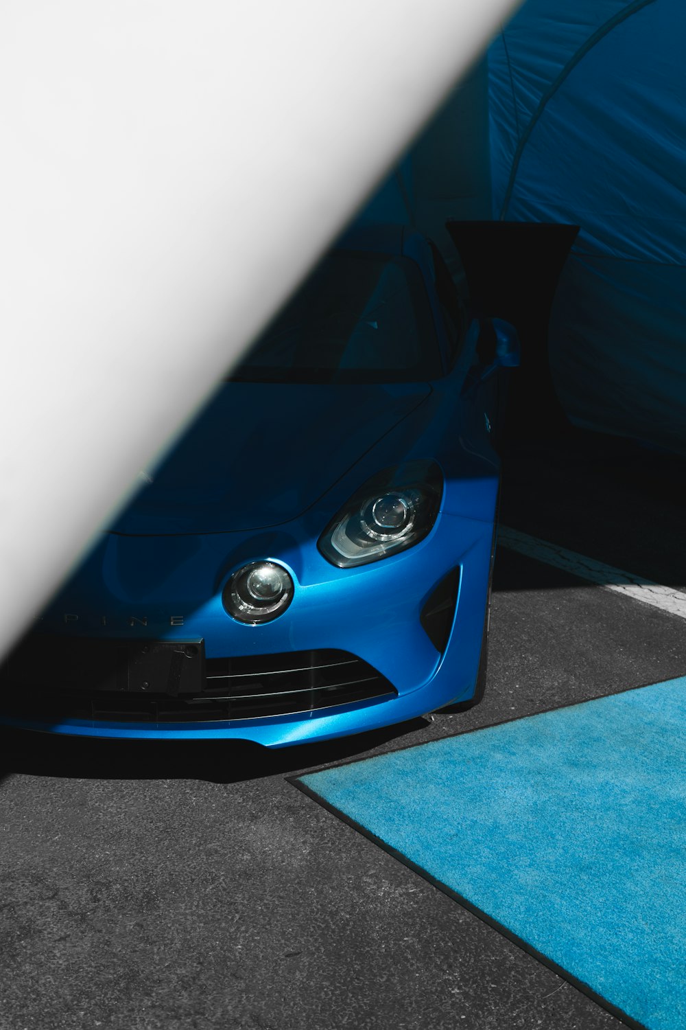 a blue sports car parked next to a tent
