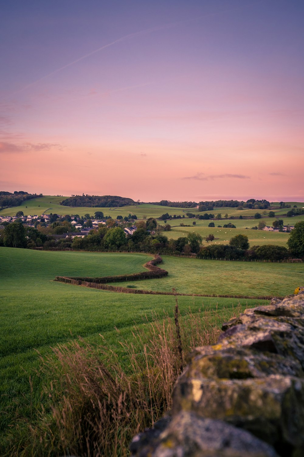 a grassy field with a stone wall in the foreground