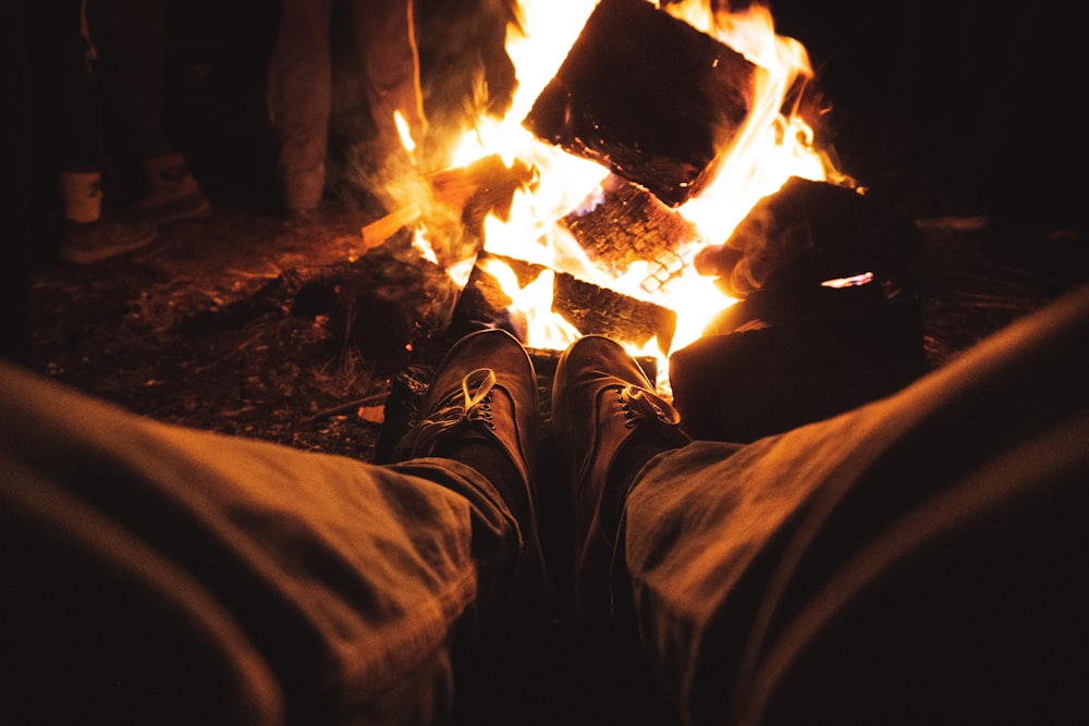 a person sitting in front of a fire with their feet up