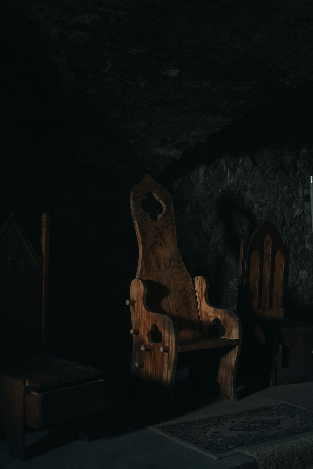 Una silla de madera sentada en una habitación oscura