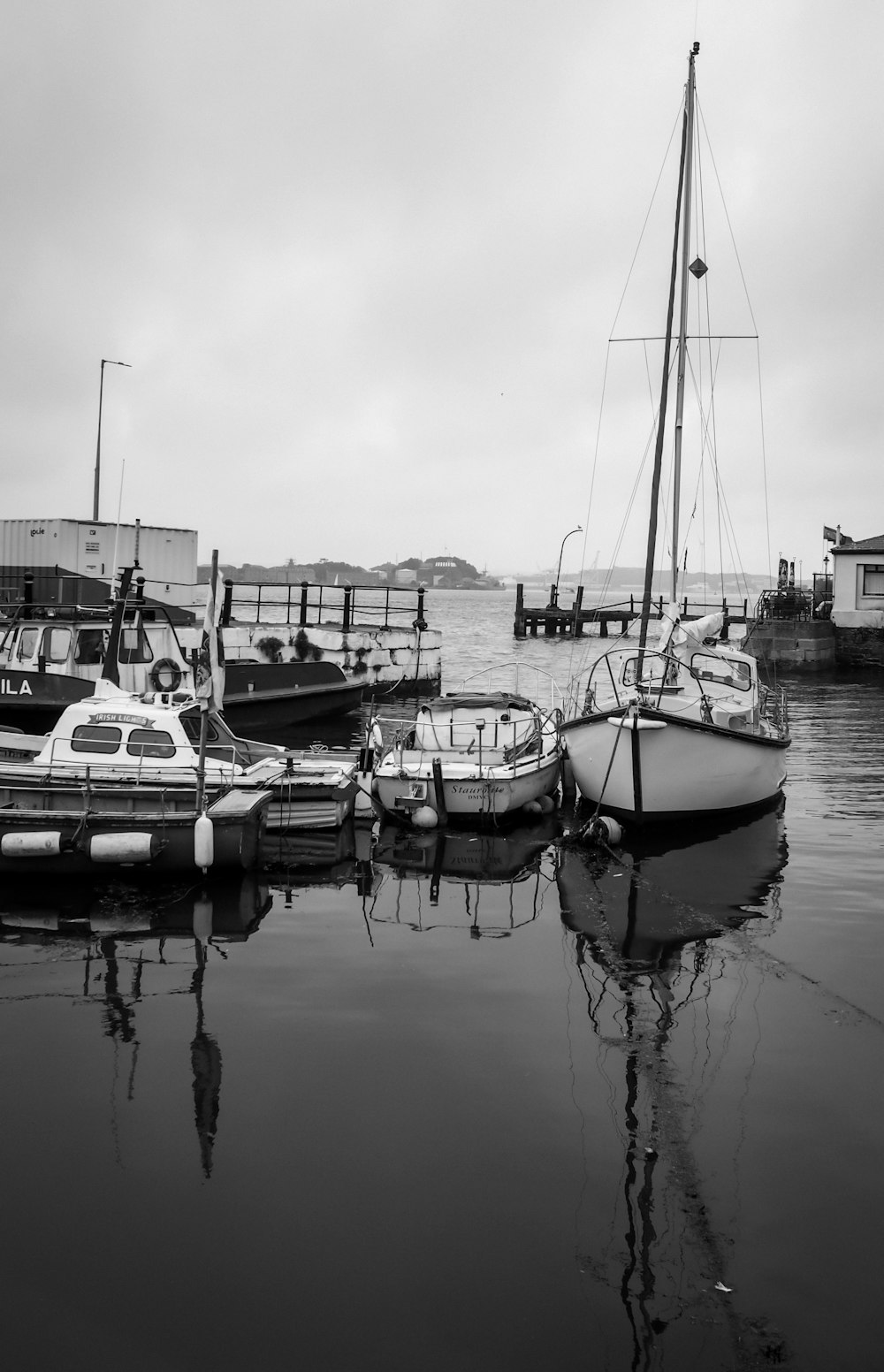 a black and white photo of boats docked at a pier