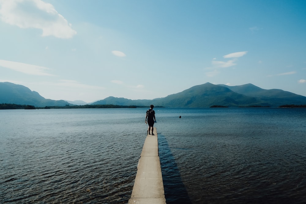 a person standing on a pier looking out at the water