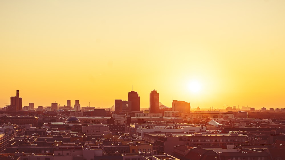 the sun is setting over a city with tall buildings