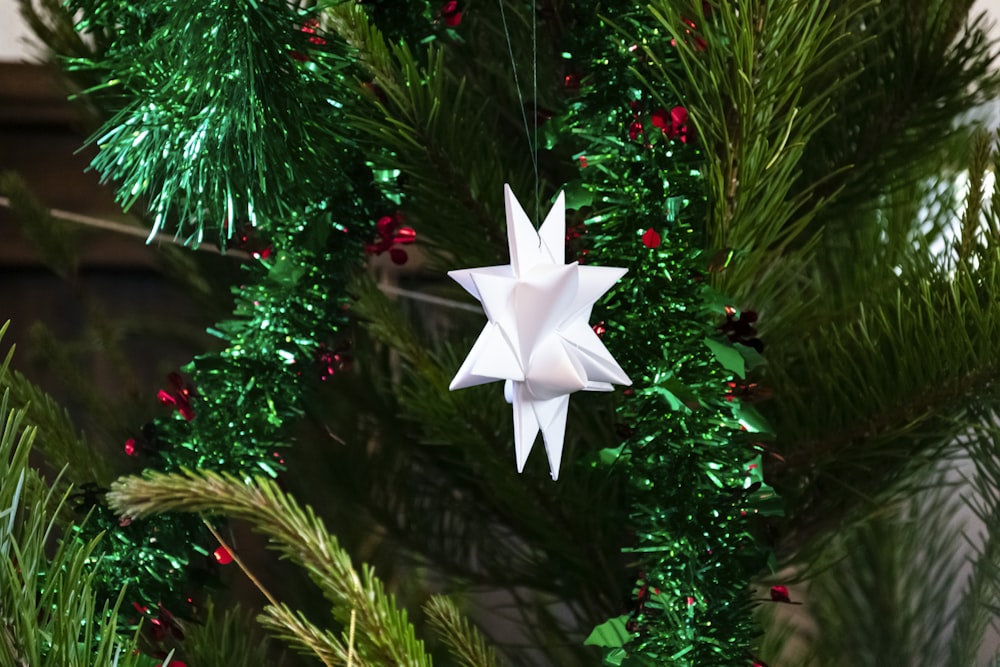 a white origami star hanging from a christmas tree