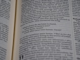 Open book displaying a passage from the Bible with a focus on the text centered on the page. The text is in black font on white paper, with some underlined words indicating emphasis.