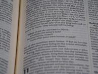 Open book displaying a passage from the Bible with a focus on the text centered on the page. The text is in black font on white paper, with some underlined words indicating emphasis.