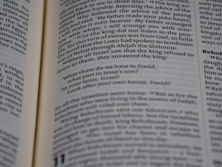 Open book displaying a passage from the Bible with a focus on the text centered on the page. The text is in black font on white paper, with some underlined words indicating emphasis.