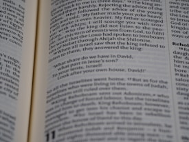 Open book displaying a passage from the Bible with a focus on the text centered on the page. The text is in black font on white paper, with some underlined words indicating emphasis.