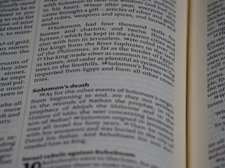 A close-up of a book's pages, with text detailing events from a biblical narrative about Solomon. The focus is on a section discussing Solomon's wealth, horses, and death.