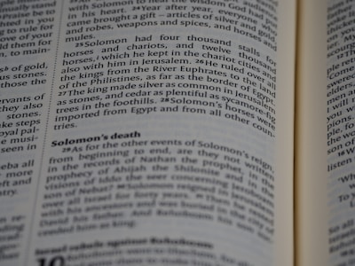 A close-up of a book's pages, with text detailing events from a biblical narrative about Solomon. The focus is on a section discussing Solomon's wealth, horses, and death.