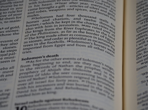 A close-up of a book's pages, with text detailing events from a biblical narrative about Solomon. The focus is on a section discussing Solomon's wealth, horses, and death.