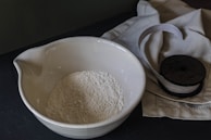 a bowl of flour next to a wooden spoon