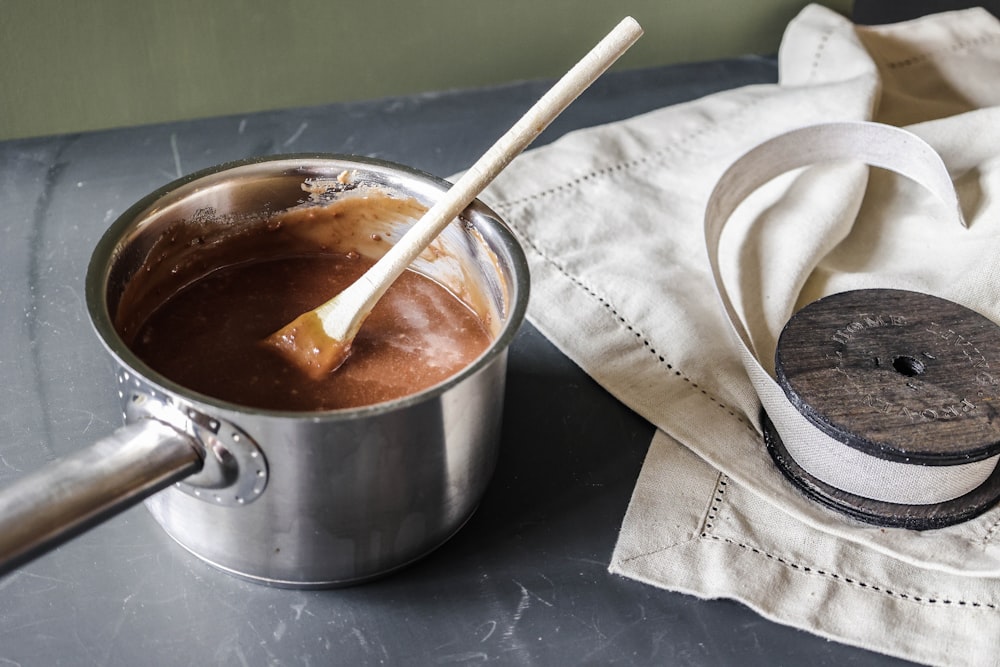 a pot of chocolate and a wooden spoon on a table