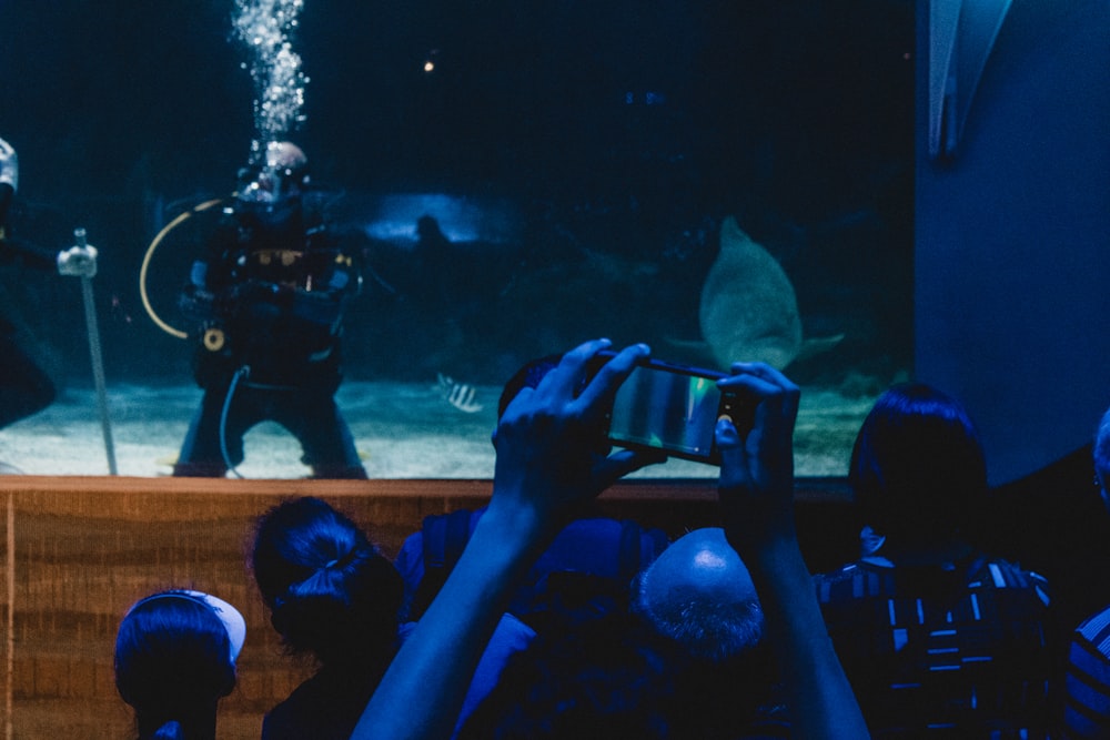a group of people taking pictures of an aquarium