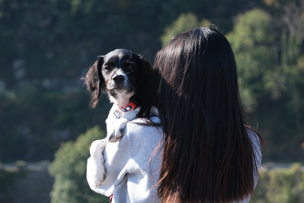 uma mulher segurando um cão em seus braços