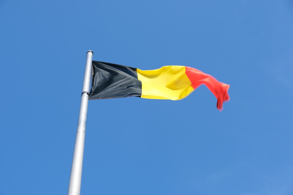 a black, yellow and red flag flying in the sky