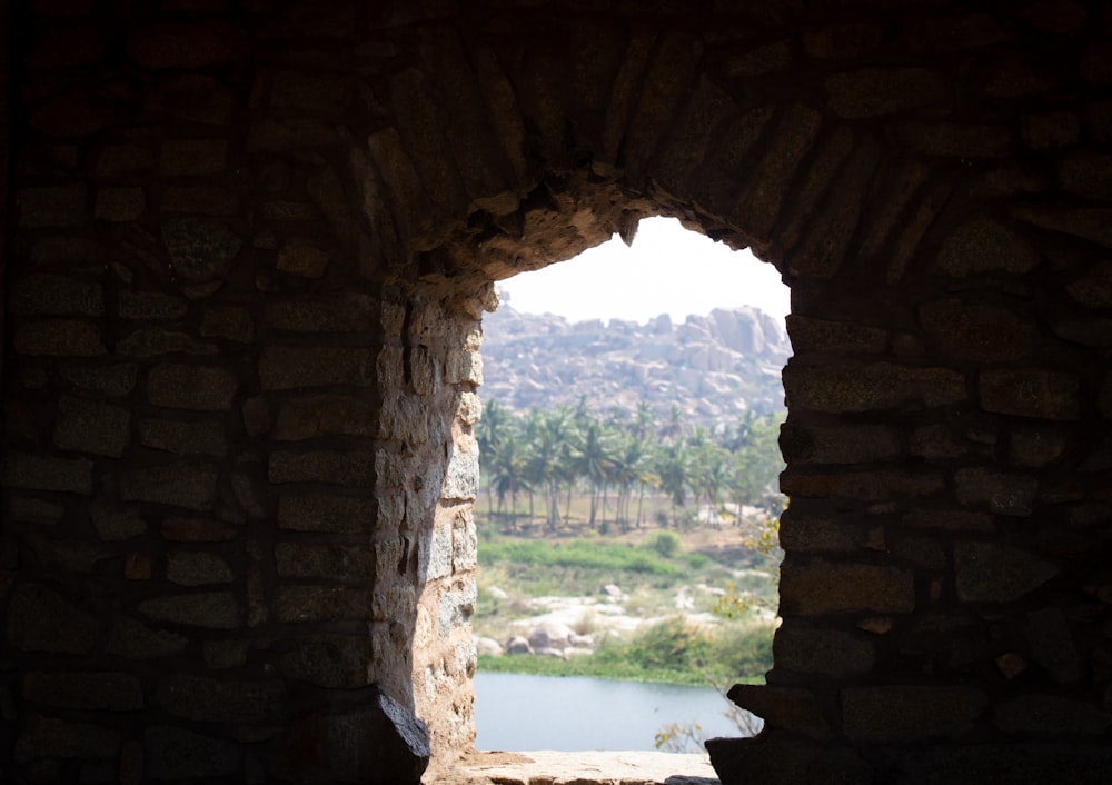 a window in a stone wall with a view of a river